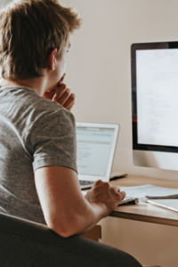 teen in gray tee shirt uses desktop computer