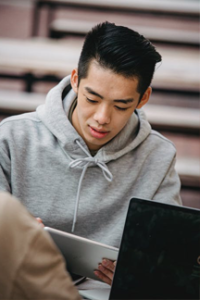 student in gray hoodie uses ipad