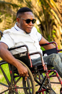 young adult in wheelchair and sunglasses crosses campus