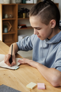 student writes in journal while sitting at desk