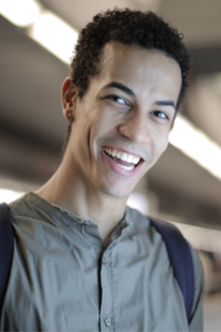 teen in gray shirt and backpack smiles at camera