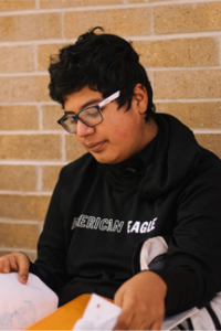 student in glasses and black hoodie looks through papers