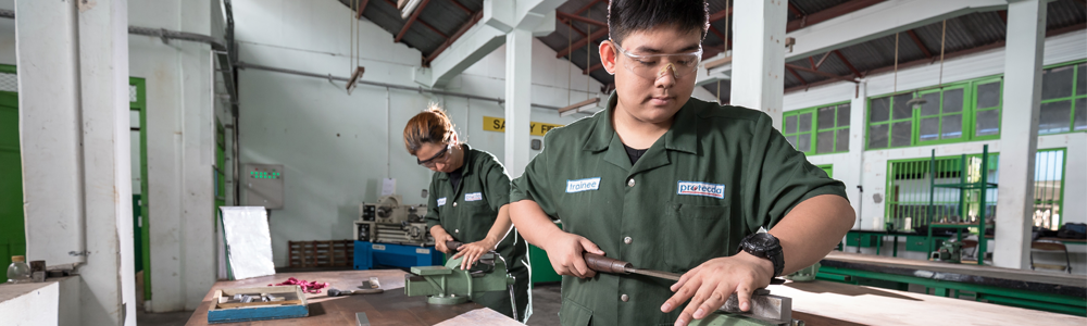 teen in coveralls and safety glasses work in shop